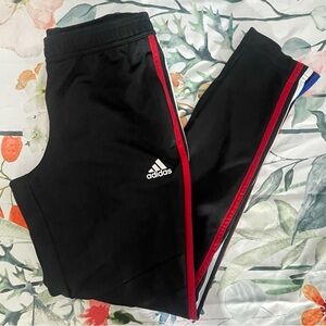 Adidas track pants with red, white, and blue stripes